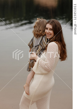 Caucasian mother holding baby standing on lake shore. 123851011