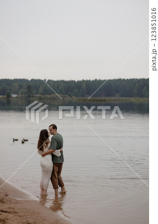 Young heterosexual couple hugging on the beach by the water Young heterosexual couple hugging on the beach by the water 123851016