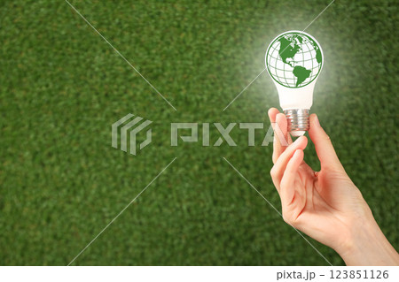 Earth Day, light bulb with Earth image in hand on green grass background, space for text Earth Day, light bulb with Earth image in hand on green grass background, space for text 123851126