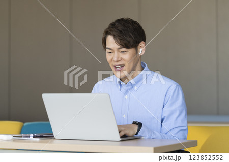 イヤホンをしてノートパソコンに向かう30代のビジネスマン 123852552