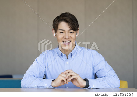 カメラ目線で話すイヤホンをつけた30代の男性 123852554