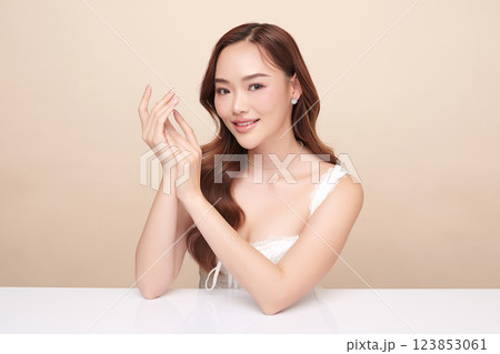 A beautiful young Asian woman with clean, fresh skin against a beige background. She represents beauty, skincare, and spa treatments. A beautiful young Asian woman with clean, fresh skin against a beige background. She represents beauty, skincare, and spa treatments. 123853061