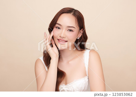 A beautiful young Asian woman with clean, fresh skin against a beige background. She represents beauty, skincare, and spa treatments. 123853062
