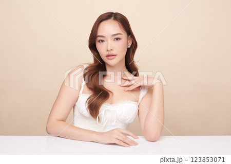 A beautiful young Asian woman with clean, fresh skin against a beige background. She represents beauty, skincare, and spa treatments. 123853071