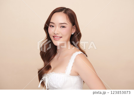 A beautiful young Asian woman with clean, fresh skin against a beige background. She represents beauty, skincare, and spa treatments. 123853073