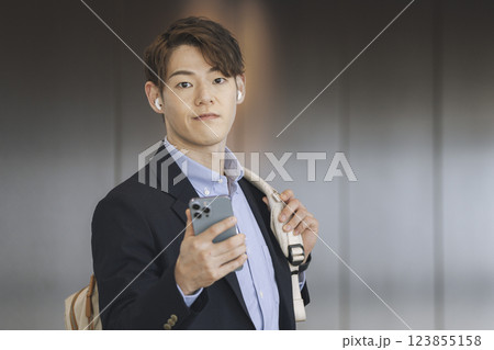 スマホを持ってイヤホンをした30代のビジネスマン スマホを持ってイヤホンをした30代のビジネスマン 123855158