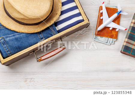 A travel bag with clothes, sun hat, flip flops, and a camera 123855348