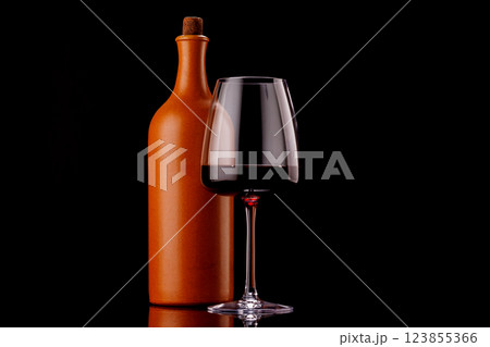 Elegant presentation of red wine in a glass and a bottle against a dark background 123855366