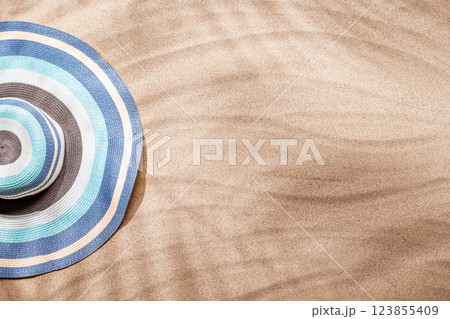 A tropical summer background featuring soft beach sand with delicate palm leaf shadows and sunhat A tropical summer background featuring soft beach sand with delicate palm leaf shadows and sunhat 123855409