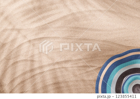 A tropical summer background featuring soft beach sand with delicate palm leaf shadows and sunhat A tropical summer background featuring soft beach sand with delicate palm leaf shadows and sunhat 123855411