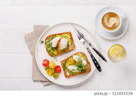 Delicious avocado toasts topped with perfectly cooked poached eggs Delicious avocado toasts topped with perfectly cooked poached eggs 123855539
