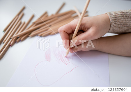 Female hand drawing heart with colored pencils on white paper 123857604