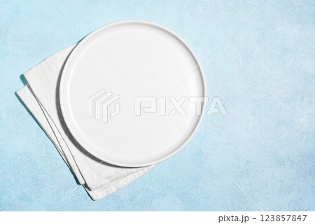 Empty white plate with napkin on blue table 123857847