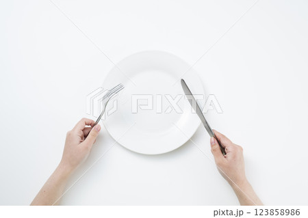 シンプルな白い皿とフォークとナイフを持つ女性 シンプルな白い皿とフォークとナイフを持つ女性 123858986