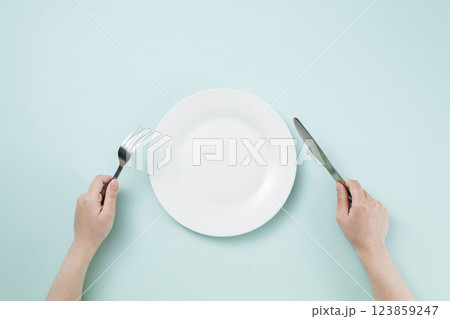 シンプルな白い皿とフォークとナイフを持つ女性の手 123859247
