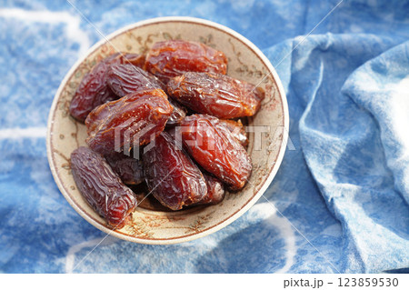 Dried dates fruit in bowl on blue cotton. Top view. 123859530