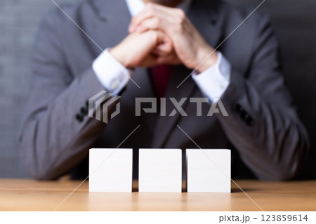 2つの白い木のブロックとスーツを着て悩むミドル男性ビジネスマン 123859614