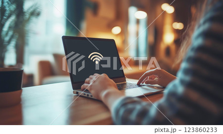 A person using a laptop in a cozy cafe encounters a no WiFi connection error on the screen, disrupting their work. 123860233