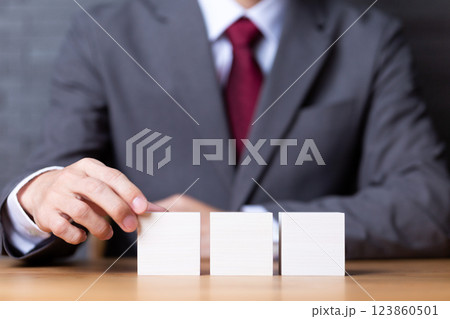 3つの白い木のブロックとスーツを着たミドル男性ビジネスマン 123860501