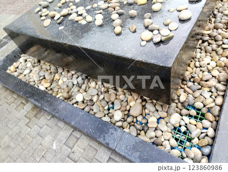 Close-up of a modern urban fountain with stones, street installation Close-up of a modern urban fountain with stones, street installation 123860986