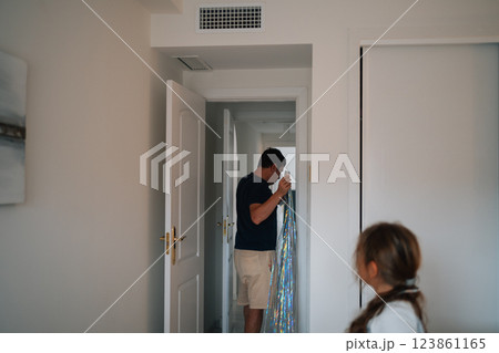 Hispanic adult male unwrapping decorated doorway as hispanic child observes in home 123861165