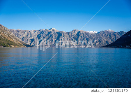 Bay of Kotor in Montenegro and the top of high snow-capped mountains, small settlements on the coast and the bright blue waters of the Adriatic Sea. 123861170