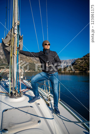 Man holding thermo mug on bow of the yacht during sailing in the morning in winter time in Adriatic sea, relaxation in yachting time 123861175