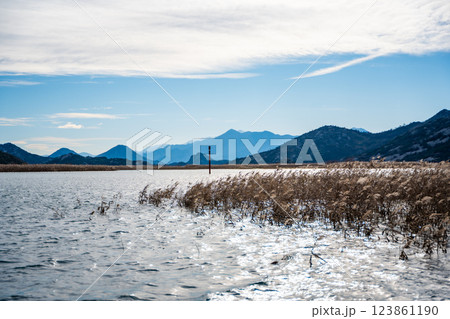 Trees and reeds on River Crnojevica, place near Lake Skadar in Montenegro surrounded by mountain peaks in winter time Trees and reeds on River Crnojevica, place near Lake Skadar in Montenegro surrounded by mountain peaks in winter time 123861190
