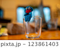 グラスのフチに座る粘土で作った青いキャラ 123861403