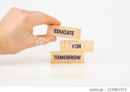 A hand arranges wooden blocks displaying the words educate for tomorrow, symbolizing the importance of education. 123861553