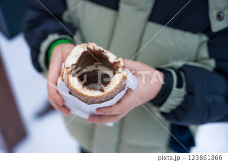 Traditional Czech trdelnik with chocolate filling held by a child in winter Traditional Czech trdelnik with chocolate filling held by a child in winter 123861866