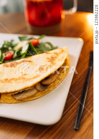 Tortilla with champignons with salad in a square white plate Tortilla with champignons with salad in a square white plate 123862228