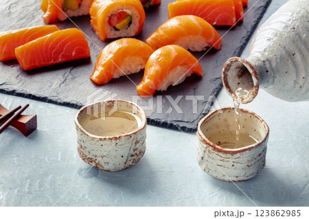 Sake poured into ochoko, traditional cup, with salmon nigiri and sashimi Sake poured into ochoko, traditional cup, with salmon nigiri and sashimi 123862985