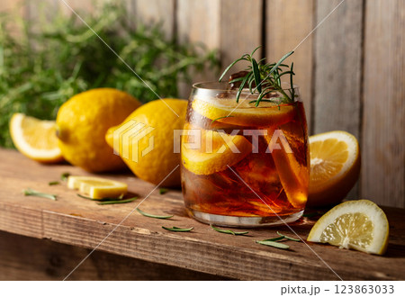 Hard seltzer or alcoholic cocktail with ice, rosemary and lemon slices on a old wooden table. 123863033