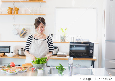 キッチンで料理をするエプロン姿の女性 123863052