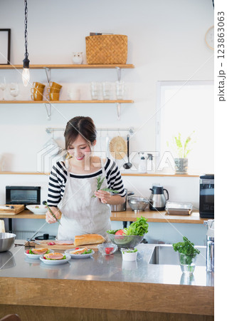 キッチンで料理をするエプロン姿の女性 123863063
