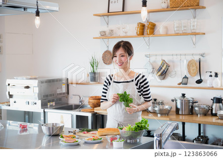 キッチンで料理をするエプロン姿の女性 キッチンで料理をするエプロン姿の女性 123863066