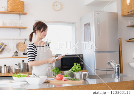 キッチンで料理をするエプロン姿の女性 123863113