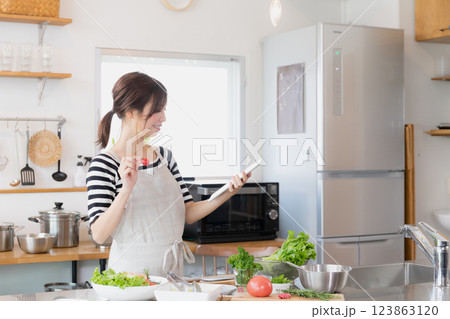 キッチンで料理をするエプロン姿の女性 キッチンで料理をするエプロン姿の女性 123863120