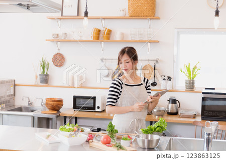 キッチンで料理をするエプロン姿の女性 キッチンで料理をするエプロン姿の女性 123863125
