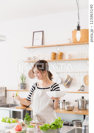 キッチンで料理をするエプロン姿の女性 キッチンで料理をするエプロン姿の女性 123863140