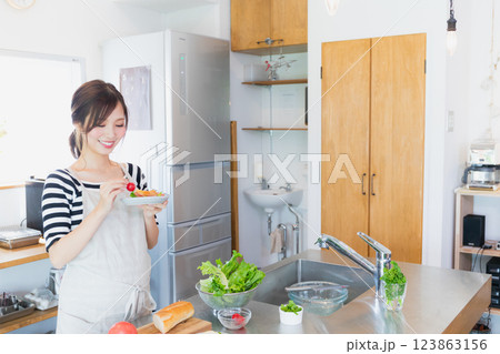 キッチンで料理をするエプロン姿の女性 キッチンで料理をするエプロン姿の女性 123863156