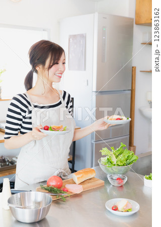 キッチンで料理をするエプロン姿の女性 キッチンで料理をするエプロン姿の女性 123863162