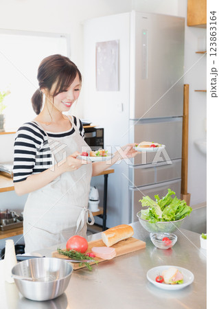 キッチンで料理をするエプロン姿の女性 キッチンで料理をするエプロン姿の女性 123863164
