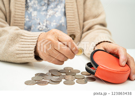 Asian senior or elderly old lady woman holding counting coin money in purse. Poverty, saving problem in retirement. Asian senior or elderly old lady woman holding counting coin money in purse. Poverty, saving problem in retirement. 123863438
