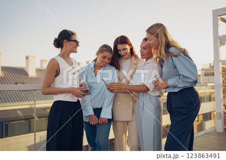 A group of close friends happily enjoying a beautiful sunset while gathered on a rooftop A group of close friends happily enjoying a beautiful sunset while gathered on a rooftop 123863491