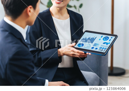 ロビーでタブレットを見ながら商談する男女ビジネスパーソンのグループ ロビーでタブレットを見ながら商談する男女ビジネスパーソンのグループ 123864006