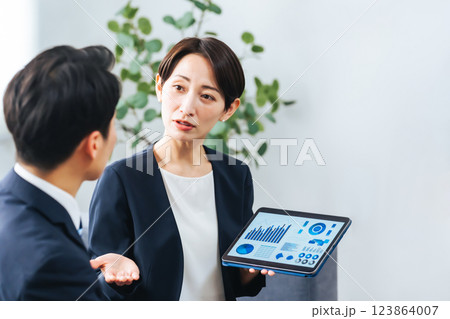 ロビーでタブレットを見ながら商談する男女ビジネスパーソンのグループ 123864007