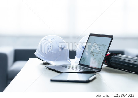 オフィスに置かれたノートパソコンとヘルメット オフィスに置かれたノートパソコンとヘルメット 123864023