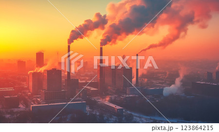 Smoke billows from industrial chimneys at sunset over an urban landscape in winter 123864215